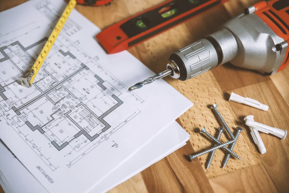 Floor plan on a table with a drill and a tape measure